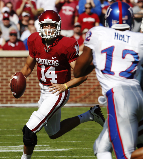 Oklahoma quarterback Sam Bradford, left, looks for a receiver as Kansas linebacker James Holt (12) moves in during the first quarter of an NCAA college football game in Norman, Okla., Saturday, Oct. 18, 2008. Bradford passed for an Oklahoma record 468 yards and had three touchdowns passes to help the No. 4 Sooners bounce back from their first loss by beating No. 16 Kansas 45-31. (AP)